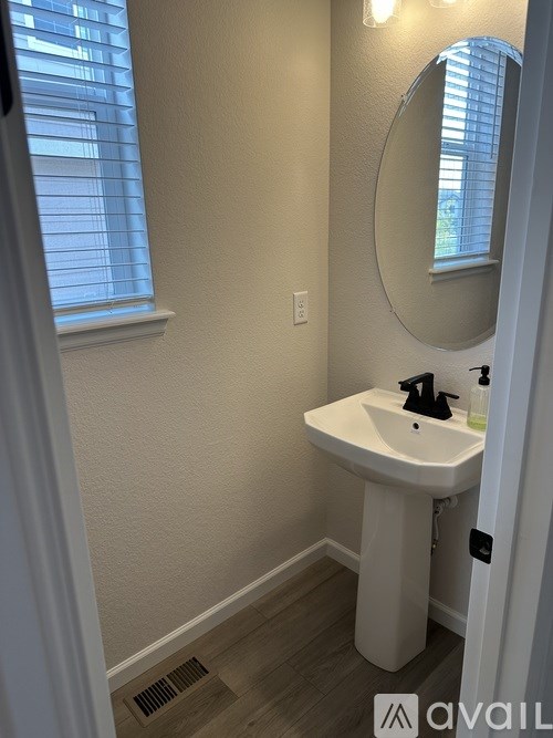 A bathroom with a white sink and a round mirror.