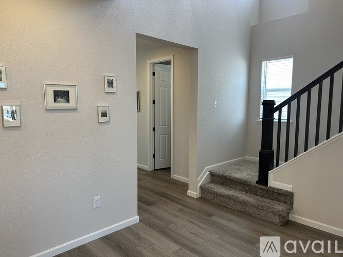 A hallway with a staircase and pictures on the wall.