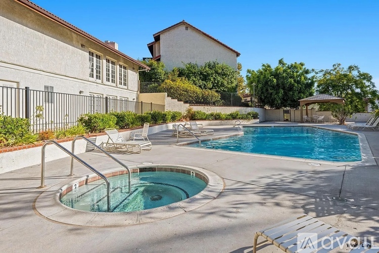 A hot tub sits in the middle of a pool surrounded by a concrete patio.