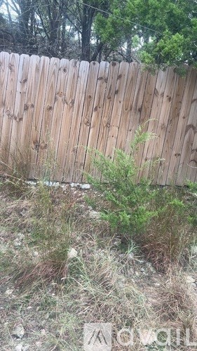 A wooden fence with grass and weeds in front of it.