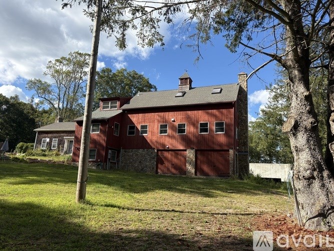 A red barn with a stone foundation and a green roof.