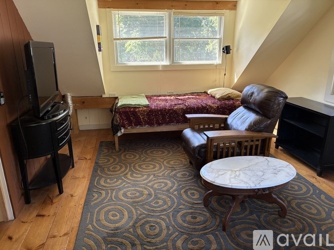 A bedroom with a bed, a chair, and a television.