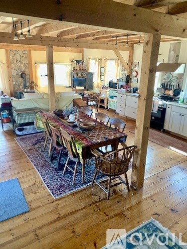 A dining room with a table surrounded by chairs.