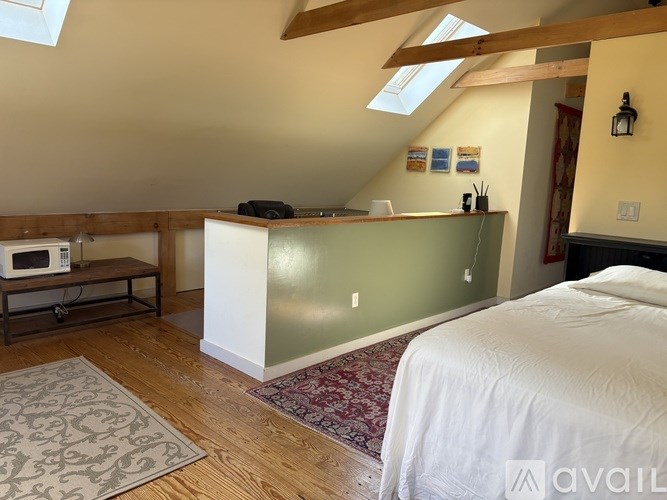 A bedroom with a bed, a desk, and a window.