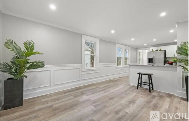 A spacious kitchen with wooden flooring and white walls.