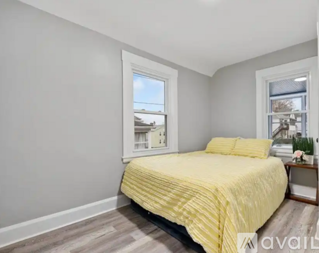 A bedroom with a yellow bedspread and a window overlooking a building.