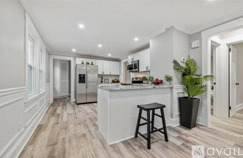 A kitchen with white cabinets and a wooden floor.