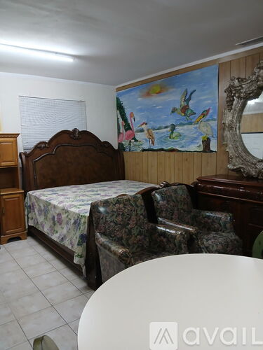 A bedroom with a bed, chair, and a painting on the wall.