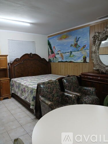 A bedroom with a bed, chair, and a painting on the wall.