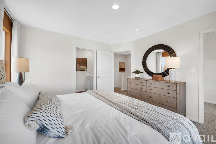 A bedroom with a large bed and a dresser with a mirror above it.