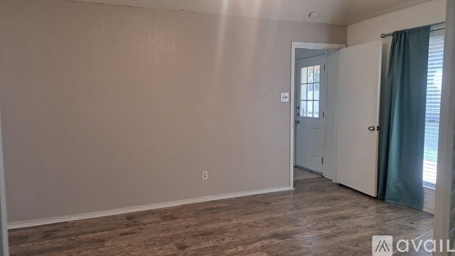 A room with a door and a window with a curtain.