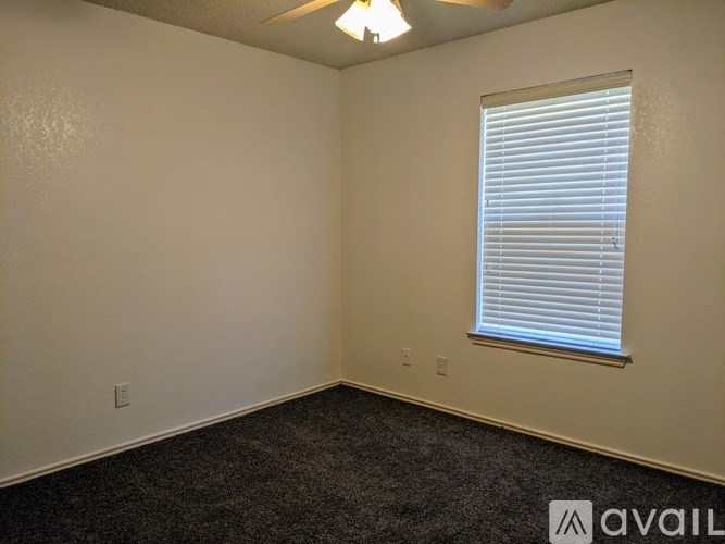 A room with a window covered by blinds and a carpet on the floor.