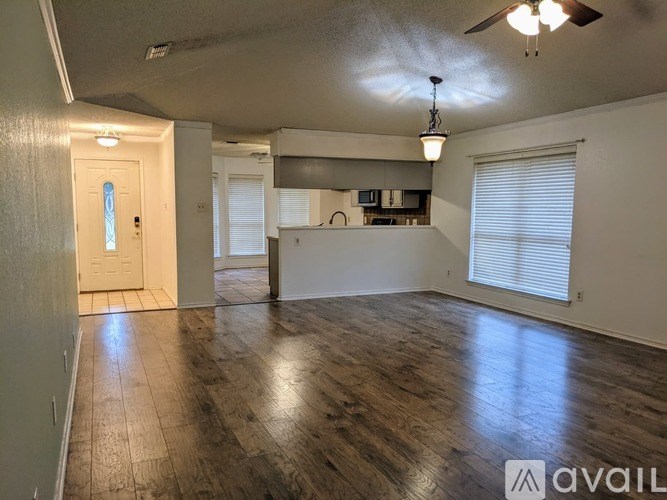A spacious room with wooden flooring and a ceiling fan.