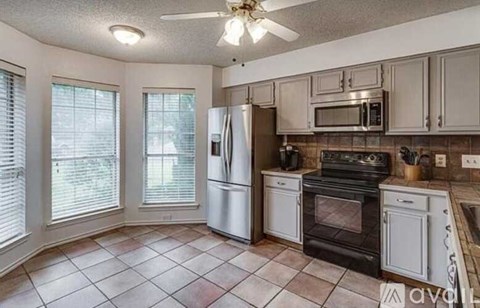 A kitchen with a black stove top oven and white cabinets.