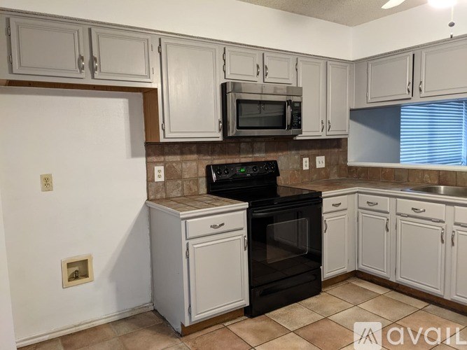 A kitchen with white cabinets and a black stove top oven.