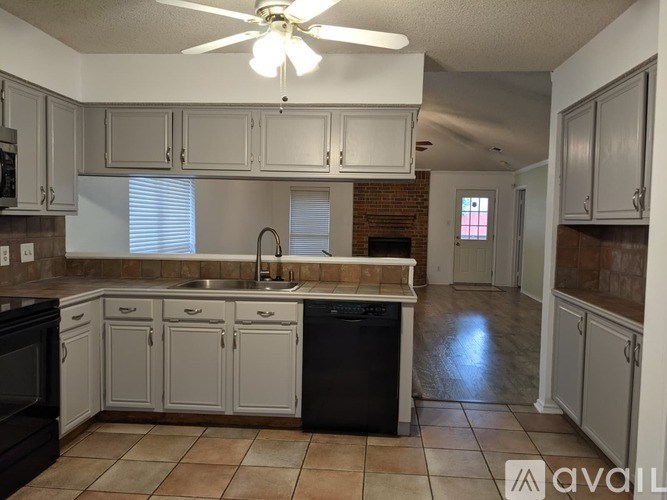 A kitchen with a black dishwasher and white cabinets.