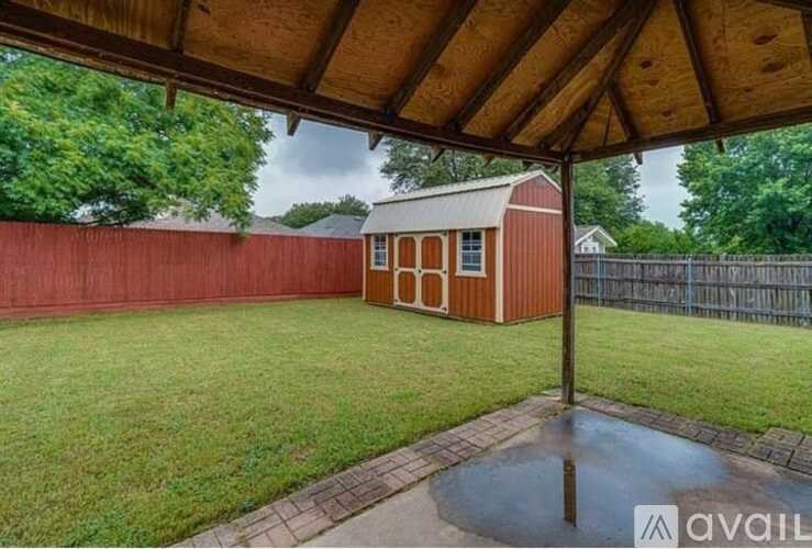 A red shed sits in a grassy backyard.