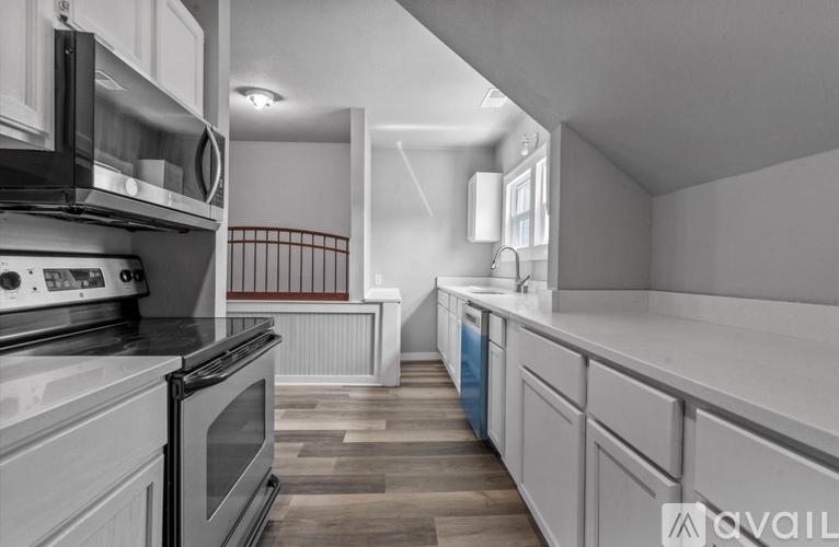 A modern kitchen with white cabinets and a wooden floor.