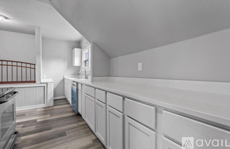 A kitchen with white cabinets and a wooden floor.