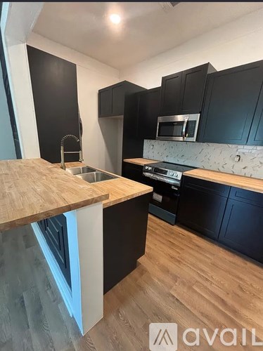 A kitchen with black cabinets and a wooden countertop.