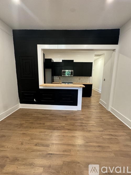 A kitchen with black cabinets and a wooden floor.