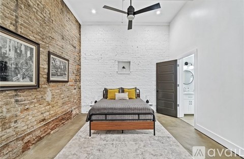 A bedroom with a brick wall and a bed with a wooden frame.