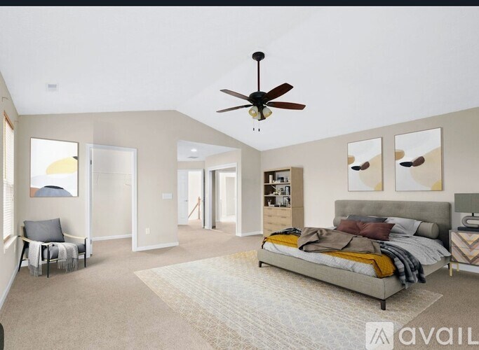 A bedroom with a bed, a chair, and a ceiling fan.