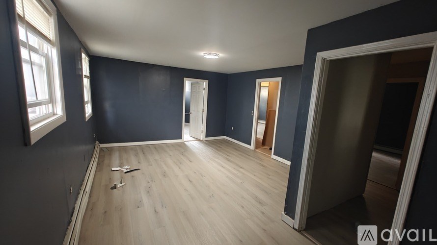 A room with wooden flooring and a window on the left side.