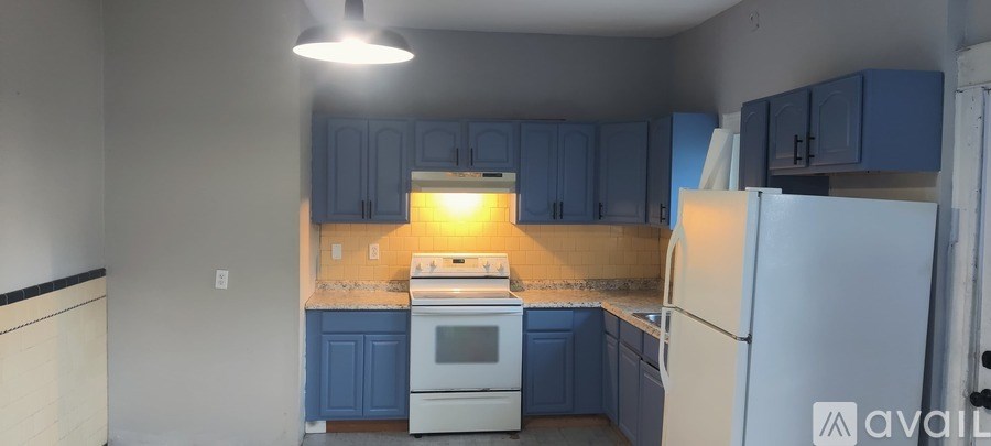 A kitchen with blue cabinets and a white refrigerator.