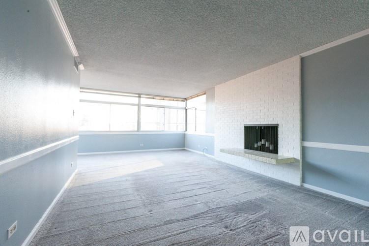 A spacious living room with a fireplace and large windows.