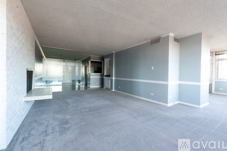 A spacious room with a grey carpet and white walls.