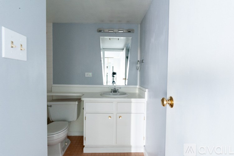 A bathroom with a toilet, sink and mirror.