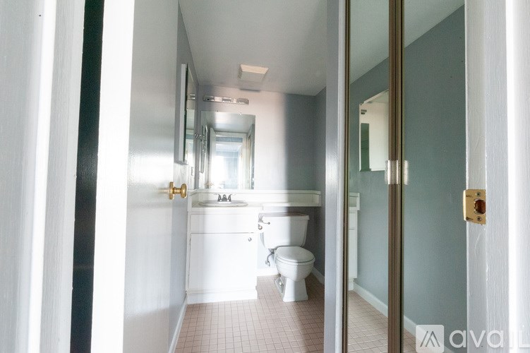 A bathroom with a toilet, sink, and mirror.