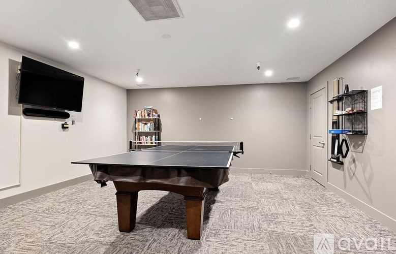 A room with a table, a television, and a bookshelf.