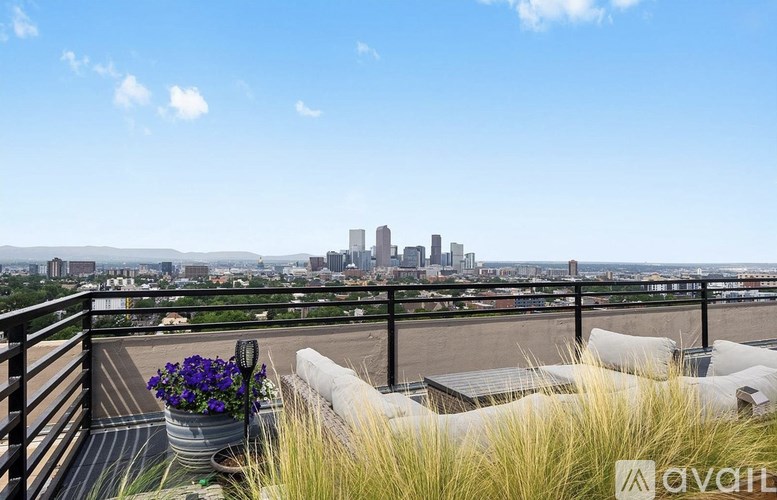 A balcony with a view of a city skyline and a potted plant with purple flowers.