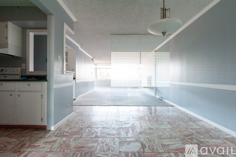 A kitchen with a marble floor and a window letting in sunlight.
