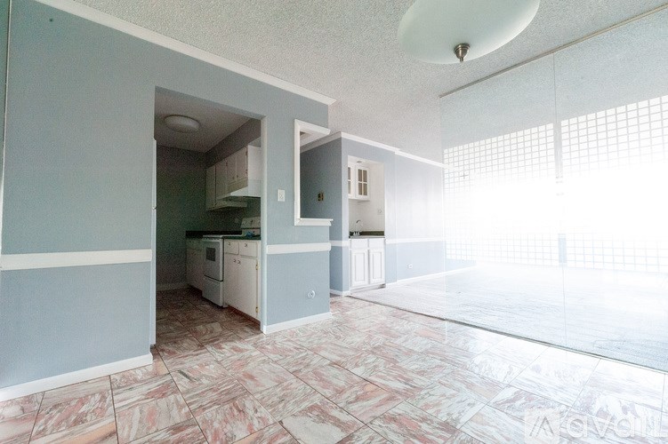 A kitchen with a refrigerator, microwave, and oven is visible through an open door.