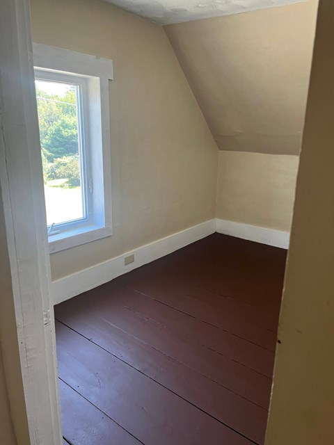 A room with a window and wooden flooring.