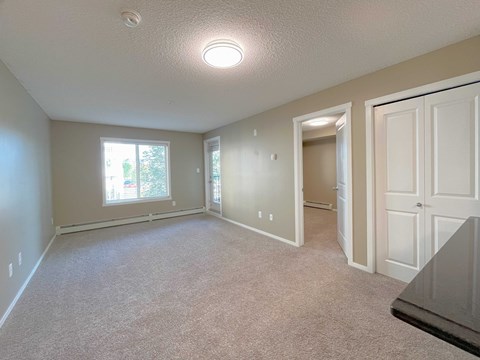 A spacious room with a carpeted floor and a window.