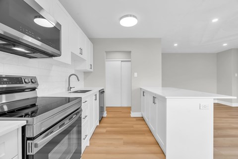 A modern kitchen with white cabinets and stainless steel appliances.