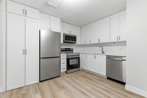 A kitchen with white cabinets and a stainless steel refrigerator.