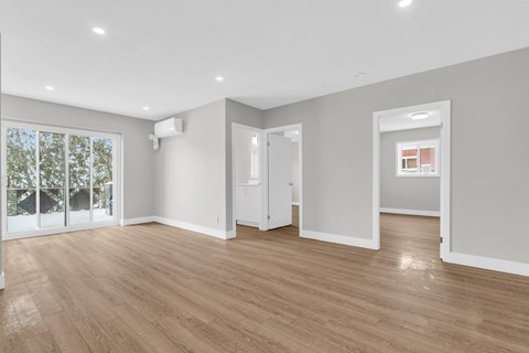 A spacious room with wooden flooring and white walls.
