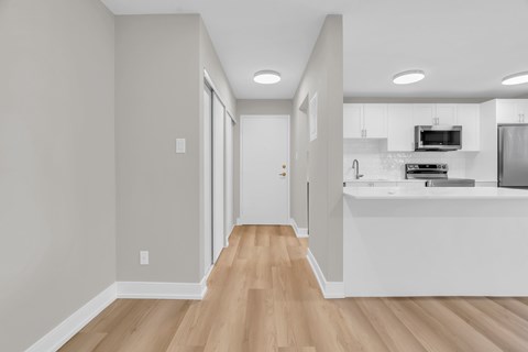 A kitchen with white cabinets and a wooden floor.
