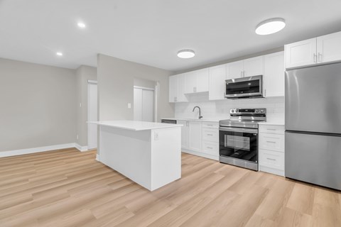 A modern kitchen with wooden floors and stainless steel appliances.