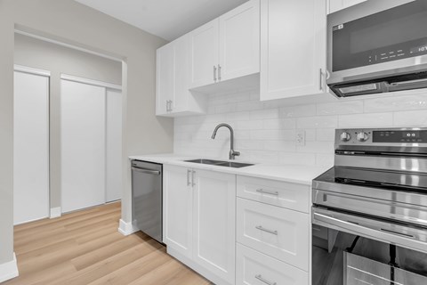 A modern kitchen with white cabinets and stainless steel appliances.