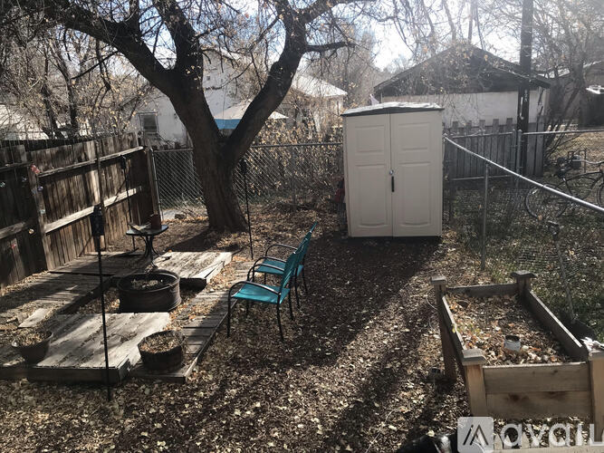 A garden with a shed, a bench and a fence.