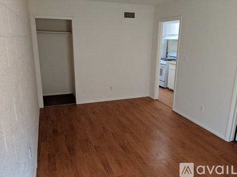 A room with wooden flooring and white walls, with a doorway leading to another room.