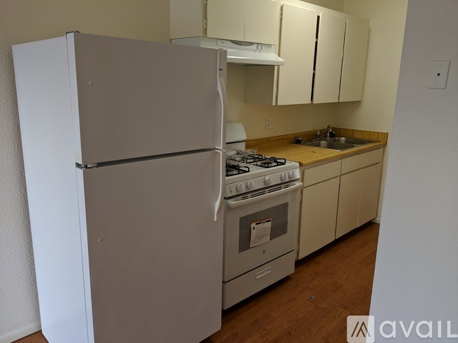 A kitchen with a white refrigerator, stove, and cabinets.