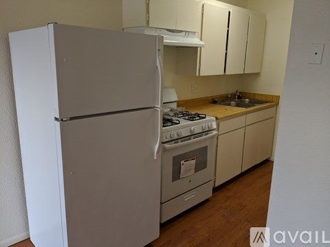 A kitchen with a white refrigerator, stove, and cabinets.