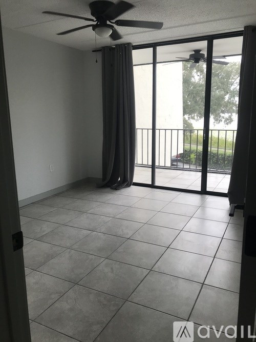 A room with a ceiling fan and sliding glass doors leading to a balcony.